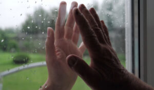 Hospice Care, two hands on window