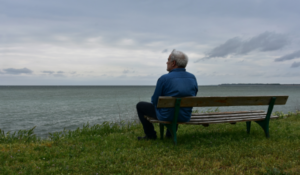 man sitting looking at the ocean